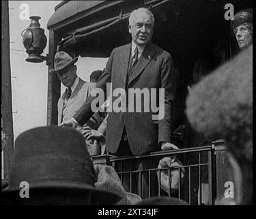 US-Senator aus Ohio und Präsidentschaftskandidat Warren Harding sprachen mit seiner Frau Florence Harding (1920) von der Rückseite eines Eisenbahnwaggons zu Amerikanern. Mr. Harding, der neu gewählt wurde, wollte aufräumen, aber aufräumen ohne grundlegende Veränderung. Denn Mr. Harding war ein großer Vertreter der Denkschule. Aus "Time to Remember - the Plunge into Peace", 1920 (Reel 2); Ereignisse von 1920 - Hochzeiten, Frauenrechte, industrielle Unruhen und Probleme in Irland Stockfoto