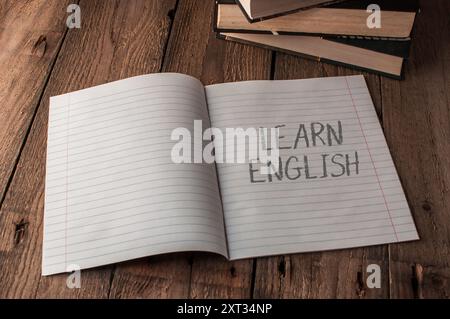 Ein Notizbuch ist offen für eine Seite, auf der das Wort Learn english steht. Das Notizbuch sitzt auf einem Holztisch Stockfoto