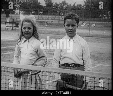 Britische Tennisspielerin Betty Nuttall as a Child, stehend auf einem Tennisplatz mit einem jungen Jungen, 1921. Aus "Time to Remember - The Time When Little Happened", 1921 (Reel 2); Ereignisse von 1921 - Irish treaty, Mad Stunts and Newspapers at Work. Stockfoto