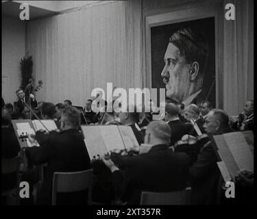 Orchester spielt mit einem Porträt von Adolf Hitler im Hintergrund, 1930er Jahre Aus „Time to Remember – the Powers that WHO WE“, 1930er Jahre (Walze 1); ein Dokumentarfilm über verschiedene wichtige Figuren der 1930er Jahre Stockfoto