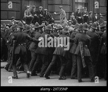 Britische Polizeibeamte halten Menschenmassen von Demonstranten in der Downing Street, London, 1920 zurück. "Als George Lansbury und andere gewerkschaftsführer in die Downing Street gingen, um über Großbritanniens wachsende Arbeitsprobleme zu diskutieren, diente ein Konflikt zwischen Polizei und Demonstranten dazu, zu zeigen, dass dies ein Frieden war, der keineswegs so viel versprechend war, wie er gewesen sein könnte." Aus "Time to Remember - the Plunge into Peace", 1920 (Reel 4); Ereignisse von 1920 - Hochzeiten, Frauenrechte, industrielle Unruhen und Probleme in Irland Stockfoto