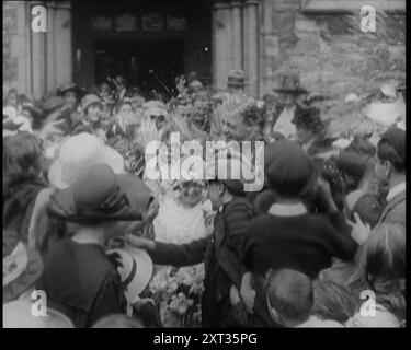 Britische Braut und Bräutigam verlassen eine Kirche nach ihrer Hochzeitszeremonie. Die Gäste werfen Reis und Konfetti, 1921. Aus "Time to Remember - The Time When Little Happened", 1921 (Reel 1); Ereignisse von 1921 - Irish treaty, Mad Stunts and Newspapers at Work. Stockfoto