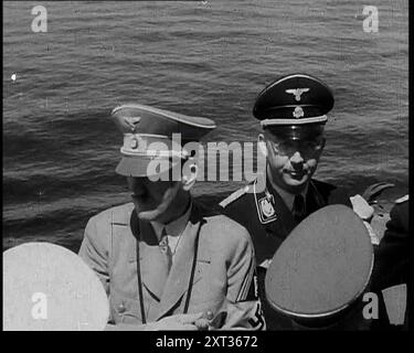 Adolf Hitler und Heinrich Himmler an Bord eines italienischen Kriegsschiffes, 1937. "Auf der Brücke eines Kriegsschiffes im Mittelmeer, der Führer aller Deutschen wird vom Führer aller Italiener unterhalten (und wir meinen nicht den König von Italien). Die Jungs waren alle zusammen da, inspizierten die italienische Flotte und schätzten ihre Kampfkraft ab, sollte es Ärger geben. Aus "Time to Remember - Sense of Values", 1937 (Reel 1); Dokumentarfilm über die Ereignisse von 1937, Krieg im Fernen Osten, Aufbau bis Krieg in Europa. Stockfoto