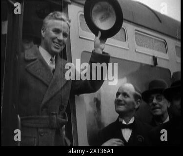 Charlie Chaplin grüßt Zuschauer aus einem Zug, 1930er Aus "Time to Remember - Some People in the Thirties", 1930er Jahre (Rolle 1); Dokumentarfilm über die 1930er Jahre, der sich auf berühmte Charaktere dieser Zeit konzentriert. Stockfoto