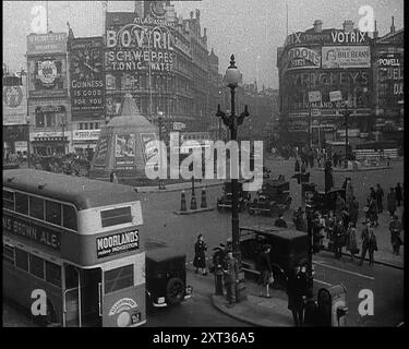 Menschen und Verkehr bewegen sich durch den Piccadilly Circus in London, 1940. Großbritannien während des Zweiten Weltkriegs: Churchills Rede über die Bedrohung durch Nazi-Deutschland: "Die ganze Wut und Macht des Feindes muss sehr bald gegen uns gerichtet werden. Hitler weiß, dass er uns auf dieser Insel brechen muss, oder den Krieg verlieren muss. Wenn wir uns ihm stellen können, könnte ganz Europa frei sein und das Leben der Welt in weite, sonnendurchflutete Berggebiete vordringen. Aber wenn wir scheitern, dann wird die ganze Welt, einschließlich der Vereinigten Staaten, einschließlich all dessen, was wir kannten und pflegten, in den Abgrund eines neuen dunklen Zeitalters versinken, das mehr wird Stockfoto