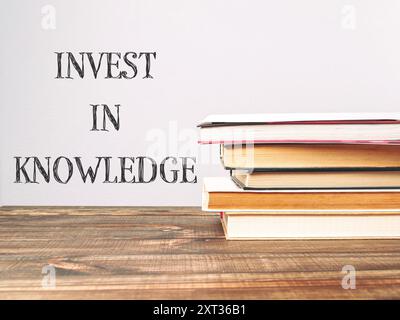 Ein Stapel Bücher mit den Worten Invest in Knowledge, die oben geschrieben sind. Das Bild vermittelt die Vorstellung, dass das Lernen und das Erlernen von Wissen wertvoll ist Stockfoto