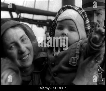 Niederländische Flüchtlinge flüchten an Bord von Schiffen in den Niederlanden. Eine Frau, die ihr Baby hält, lächelt in die Kamera, 1940. Zweiter Weltkrieg. "Wichtig und unwichtig - sie kamen nach Großbritannien. Die Verfolgten, die Unschuldigen, die Juden, die Katholiken, die Protestanten, die unerwünschten, die Ungläubigen an die bösen Mächte, die sind. Aber für diejenigen, die noch frei sind, gibt es keine größeren Verbündeten als diejenigen, die die Knechtschaft kennen und ihre Ketten verlassen haben." Aus Time to Remember - Run Rabbit Run, 1940 ( Reel 2); Dokumentarfilm über Ereignisse der frühen Monate 1940. Stockfoto