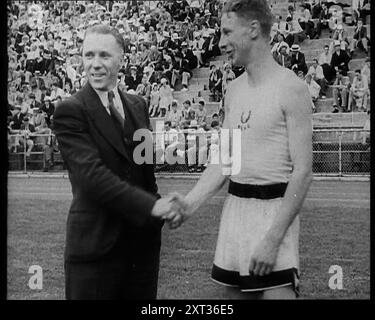 Jack Lovelock schüttelt mit jemandem die Hand, als die Massen zusehen, 1930er Aus "Time to Remember - Some People in the Thirties", 1930er Jahre (Reel 2); Dokumentarfilm über die 1930er Jahre, der sich auf berühmte Charaktere dieser Zeit konzentriert. Stockfoto