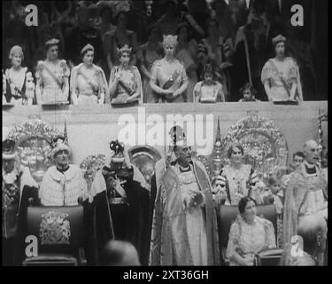 Weibliche Mitglieder der königlichen Familie, darunter Königin Gemahlin Maria von Teck, Prinzessinnen Elizabeth und Margaret, und die Herzoginnen von Gloucester und Kent, die die Krönung von König Georg VI. Mit verschiedenen königlichen Persönlichkeiten und Geistlichen unter und vor ihnen beobachteten, 1937. "Eine Krönung in Großbritannien, ihr Ablauf, ihre Insignien, ihre Zeremonie wie immer - nur die Figuren ändern sich mit jeder Gelegenheit... Zeremonie für einen Monarchen... seine Majestät König Georg VI. Wird gefeiert!" Aus "Time to Remember - Sense of Values", 1937 (Reel 4); Dokumentarfilm über Stockfoto