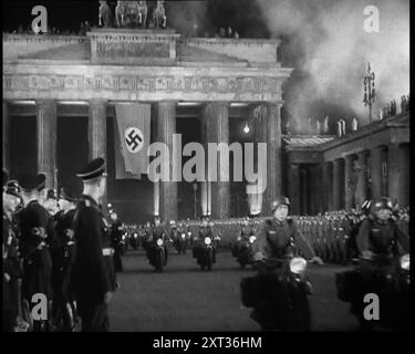 Deutsche Offiziere und Soldaten säumen den Pariser Platz am Brandenburger Tor, an dem eine deutsche Flagge hängt, als Formation von männlichen Motorradfahrern Pass By, 1937. Berlin. "Der Anführer [Adolf Hitler] kehrt von seinem Italienbesuch zurück... den Menschen wird gesagt, dass der Anführer nicht nur ein Mann ist, sondern ein makelloser Gott, und als solcher behandelt werden muss - und so behandelt wird er. Nicht die Rückkehr eines erobernden Helden, denn der Held hat sich noch nicht auf seine wahren Eroberungen gemacht. Nein, das ist nur die Rückkehr von Deutschlands Lieblingssohn. Etwas Neues. Etwas und jemand von treibender Kraft und Einfluss. Dies, es sei denn Stockfoto