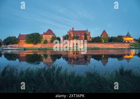 Blick auf die Burg Malbork (Zamek W Malborku), die sich in der Abenddämmerung im Wasser des Flusses Nogat spiegelt Stockfoto