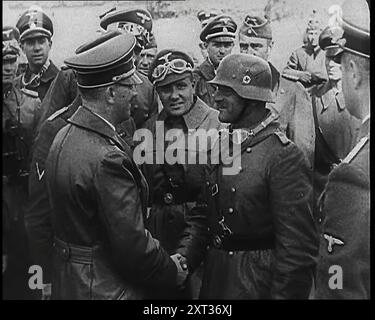 Adolf Hitler, der deutsche Führer, schüttelt die Hand mit einem deutschen Militärkommandeur, während andere Beamte und Offiziere zuschauen, 1939. Aus „Time to Remember – The Reluctant Warriors“, 1939 (Reel 3); Dokumentarfilm über Ereignisse von 1939 – Vorbereitungen für den Krieg und dann Feindseligkeiten brechen aus. Stockfoto