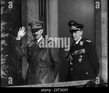 Adolf Hitler, der deutsche Führer, grüßte die Menge mit Hermann Göring auf dem Balkon des Kanzleramtes in der Wilhelmstraße, Berlin, 1937. "Der Anführer kehrt von seinem Besuch in Italien zurück... den Menschen wird gesagt, dass der Anführer nicht nur ein Mann ist, sondern ein makelloser Gott, und er muss als solcher behandelt werden - und so behandelt werden, wie er ist. Nicht die Rückkehr eines erobernden Helden, denn der Held hat sich noch nicht auf seine wahren Eroberungen gemacht. Nein, das ist nur die Rückkehr von Deutschlands Lieblingssohn. Etwas Neues. Etwas und jemand von treibender Kraft und Einfluss. Das, wenn es nicht zerstört wurde, die zukünftige Macht und die gl Stockfoto