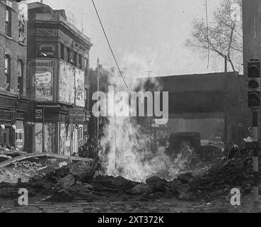 Ein brennender Bombenkrater, 1940. Großbritannien während des Zweiten Weltkriegs: Der Blitz. "Jede Nacht, zu jeder Zeit, Sommer 1940. Feuer und Flamme, Tod und Zerstörung... jeden Morgen danach in London - oder ist es Coventry, Bristol, Portsmouth? Liverpool, Belfast, Birmingham? Plymouth oder Glasgow?...bei jedem Morgen gibt es frische Verwüstungen... welche Unbekanntheit gibt es auf Ihrer allzu vertrauten Reise. Löcher, wo es gestern keine Löcher gab, keine Häuser, wo die Häuser von gestern waren. Defekte Netzleitungen spritzen Wasser, Abwasser, Gas oder Feuer. Unter den Füßen das Knirschen von zersplittertem Glas, als würde man an einem Kiesstrand laufen. Von „Zeit bis R Stockfoto