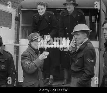 Mitglieder Des Zivilen Verteidigungskorps Trinken Tee, 1940. Großbritannien während des Zweiten Weltkriegs: Der Blitz. "Jede Nacht, zu jeder Zeit, Sommer 1940. Feuer und Flamme, Tod und Zerstörung... jeden Morgen danach in London - oder ist es Coventry, Bristol, Portsmouth? Liverpool, Belfast, Birmingham? Plymouth oder Glasgow? Guten Morgen, Arbeiter der Nacht, Zeit, als du im Bett warst - du hast es dir verdient. Aus „Time to Remember – Standing Alone“, 1940 (Reel 4); Dokumentarfilm über Ereignisse der späten Monate 1940. Stockfoto