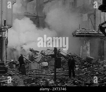 Feuerwehrleute umgeben von bombardierten Gebäuden, 1940. Großbritannien während des Zweiten Weltkriegs: Der Blitz. "Jede Nacht, zu jeder Zeit, Sommer 1940. Feuer und Flamme, Tod und Zerstörung... jeden Morgen danach in London - oder ist es Coventry, Bristol, Portsmouth? Liverpool, Belfast, Birmingham? Plymouth oder Glasgow?... gestern war die alte Ordnung. Heute ist anders, so wie morgen anders sein wird, weil es sein muss." Aus „Time to Remember – Standing Alone“, 1940 (Reel 4); Dokumentarfilm über Ereignisse der späten Monate 1940. Stockfoto