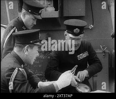 Drei männliche japanische Marineoffiziere in Uniform diskutieren Militärpläne, 1937. „Als Japan aus seiner langen Abgeschiedenheit in die moderne Welt herauskam, suchten seine Führer, inspiriert von den alten Traditionen, die alle zum Sterben für die Ehre ihres Landes aufforderten, nach Expansion und Eroberung. Die westliche Welt hatte ihnen das Schlachtschiff, die Waffe und die Bombe gegeben. Jetzt suchten sie nach der Chance, sie zu nutzen. Japan hatte eine Armee, groß und hervorragend ausgebildet. Auch eine Marine, mächtig und ehrgeizig. Es ging nur darum, wann und wo. Ein Morgen im Jahr 1937, die Küste Chinas nahe Shanghai. Eine Armada von wa Stockfoto