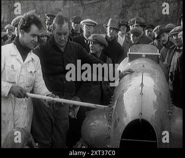 Malcolm Campbell bereitet sein Auto „Bluebird“ vor, beobachtet von einer Menge Zivilisten, 1927. Campbell mit „Bluebird“ in Pendine Sands, Carmarthenshire, bevor er im Februar 1927 den Weltrekord für Landgeschwindigkeiten brechen konnte. Aus "Time to Remember - Fast and Far in the zwanziger Jahre", 1927 (Rolle 1); ein Blick auf die Besessenheit von Geschwindigkeit und Reisen in den späten 1920er Jahren Stockfoto