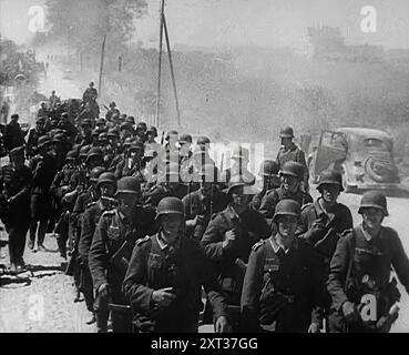 Deutsche Soldaten marschieren eine Straße hinunter, 1941. Zweiter Weltkrieg. Operation Barbarossa war die Invasion der Sowjetunion durch Nazi-Deutschland. "...die Hitler-Methode zeigte riesige Ergebnisse. An der ganzen Front waren mächtige Panzerkeile in die Massen der Roten Armee gestoßen... während dieser ersten Wochen versammelten sich die Deutschen in einer solchen Ernte [russischer Kriegsgefangener], es schien, als wäre die Niederlage der Sowjetunion sicher und sehr nahe." Aus „Time to Remember – Operation Barbarossa“, 1941 (Reel 3); Dokumentarfilm über Ereignisse von 1941, an der Ostfront und in Pearl Harbour. Stockfoto