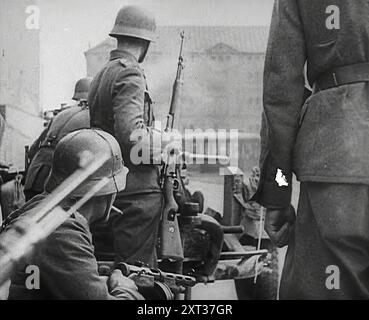 Deutsche Soldaten in einer von Bomben beschädigten Stadt, 1941. Zweiter Weltkrieg. Operation Barbarossa war die Invasion der Sowjetunion durch Nazi-Deutschland. "...die Hitler-Methode zeigte riesige Ergebnisse. An der ganzen Front waren mächtige Panzerkeile in die Massen der Roten Armee gestoßen... während dieser ersten Wochen versammelten sich die Deutschen in einer solchen Ernte [russischer Kriegsgefangener], es schien, als wäre die Niederlage der Sowjetunion sicher und sehr nahe." Aus „Time to Remember – Operation Barbarossa“, 1941 (Reel 3); Dokumentarfilm über Ereignisse von 1941, an der Ostfront und in Pearl Harbou Stockfoto