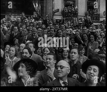 Schließen Sie einen Teil der Menschenmenge, die bei einer Militärparade zum Bastille Day beobachtet wird, und beobachten Sie die Menschen von den Balkonen des Gebäudes hinter ihnen, 1939. Aus „Time to Remember – The Reluctant Warriors“, 1939 (Reel 1); Dokumentarfilm über Ereignisse von 1939 – Vorbereitungen für den Krieg und dann Feindseligkeiten brechen aus. Stockfoto