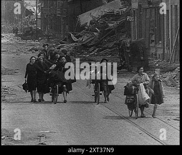 Belgische Flüchtlinge Flüchten Aus Ihrer Stadt Entlang Der Bombe Damaged Road, 1940. Zweiter Weltkrieg. „Für die Belgier ist dies die Ernte von strenger Neutralität und mangelnder Bereitschaft - Tod, Zerstörung und Chaos. Bald legt die belgische Armee auf Befehl des Königs ihre Waffen ab. Aus „Time to Remember – Run Rabbit Run“, 1940 (Reel 3); Dokumentarfilm über Ereignisse in den frühen Monaten des Jahres 1940. Stockfoto