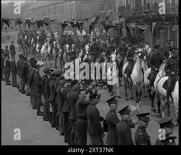 Militärparade der berittenen britischen Soldaten, die eine mit Bunting geschmückte Straße hinunterreiten, 1937. "...Trommeln, Knarren und Klappern in den Kasernen, die gefälschten Prozessionen, damit sich die Pferde an den Lärm und das Jubeln gewöhnen konnten, denn auch die Pferde müssen einen Sinn für Werte lernen, vor allem für eine Krönung." Aus "Time to Remember - Sense of Values", 1937 (Reel 1); Dokumentarfilm über die Ereignisse von 1937, Krieg im Fernen Osten, Aufbau bis Krieg in Europa. Stockfoto