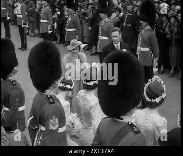 Heiratsprozession von Anne Bowes-Lyon und Lieutenant-Colonel Thomas Anson mit König George VI. Und Königin Elizabeth unter den Gästen, die eine Linie der Fußwächter und Brautjungfern hinunterlaufen, 1938. Aus „Time to Remember – Wind Up Week“, 1938 (Reel 1); Dokumentarfilm über 1938 – die Menschen werden sich der wachsenden Bedrohung des Krieges bewusst. Stockfoto