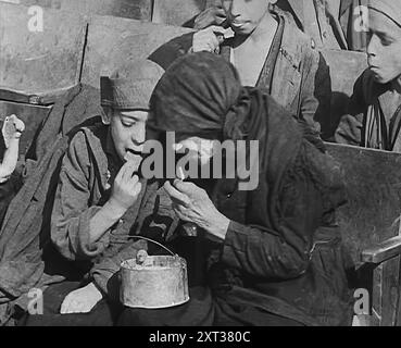 Italienische Zivilisten essen Essen in einer bombenbeschädigten italienischen Stadt, 1943-1944. Aus „Time to Remember – The Path to Rome“, 1943–1944 (Rolle 1); Dokumentarfilm über die Ereignisse von 1943 und 1944 – die italienische Kampagne. Stockfoto