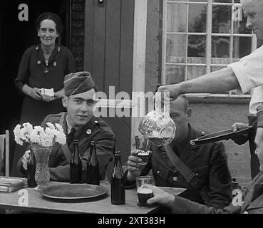 American Airmen trinken vor einem öffentlichen Haus in England und werden von der Vermieterin und Vermieterin bedient, 1943–1944. Aus „Time to Remember – Round the Clock“, 1943–1944 (Rolle 1); Dokumentarfilm über Ereignisse von 1943–1944, hauptsächlich Bombardierungen über Europa. Stockfoto