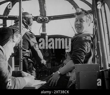 Frauen und ein Pilot sitzen im Cockpit eines Flugzeugs, 1942. Großbritannien während des Zweiten Weltkriegs. "...das Mädchen, das das Ding herstellt, das das Öl hält, das den Ring ölt, der den Schaft antreibt, der die Kurbel bewegt, die den Dingummy-bob arbeitet. Es ist eine kitzelige Art von Job, etwas für einen Dingummy-bob zu machen, besonders, wenn man nicht weiß, wofür es ist. Aber es ist das Mädchen, das das Ding macht, das das Loch bohrt, das den Ring hält, das das Ding-Ummy-bob macht, das die Motoren zum Brüllen bringt." Lyrik aus The Thing-ummy-Bob [That's Going to Win the war], einem Lied, das den f Stockfoto