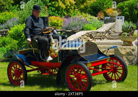 Juni 2024 American Heritage Museum - Hudson, MA. Ein Mann mit schwarzem Bowler-Hut fährt während eines Oldtimers einen rot-schwarzen Oldtimer-Roadster vom Typ A Stockfoto