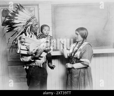 Chief Fish Wolf Robe, zwischen 1915 und 1920. Zeigt „Mamiye“, Fish Wolf Robe (1875–1966) mit einem Kind und seiner zweiten Frau „Meen-aki“, Berry Woman (1896–ca. 1972 ). Das Fish Wolf Robe war Piegan Blackfoot und Berry Woman war Chippewa Cree, die in einem Blackfoot Gebiet aufwuchs. Sie heirateten 1911. Stockfoto