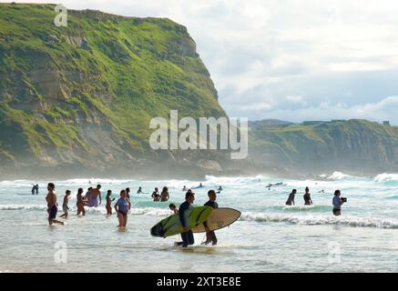 Surfer wandern mit Surfbrettern entlang des Surferstrands Playa de los Locos an einem heißen Sommertag im Juli Suances Cantabria Spanien Europa Stockfoto