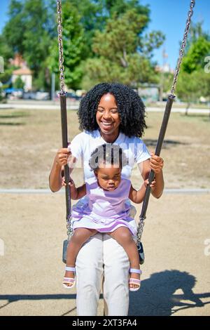 Die fröhliche afroamerikanische Mutter und ihre kleine Tochter lachen in einem sonnigen Park Stockfoto