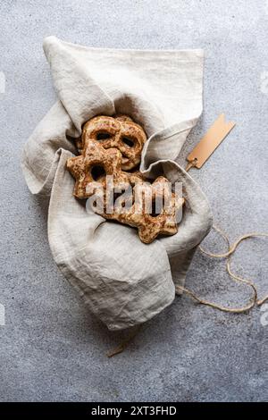 Blick von oben auf hausgemachte Lebkuchenkekse in Form von Sternen, eingebettet in einem grauen Leinentasche mit einem rustikalen Anhänger auf einer strukturierten Oberfläche. Stockfoto