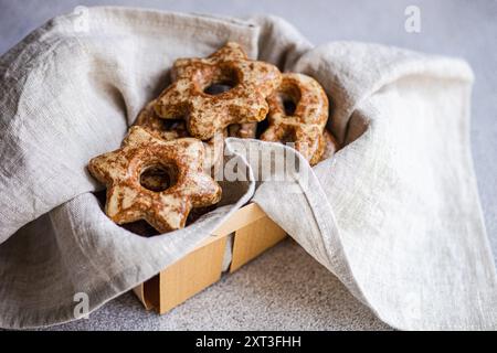 Frisch gebackene hausgemachte Lebkuchenkekse in Sternform, eingebettet in ein Leinentuch in einer rustikalen Holzkiste. Stockfoto