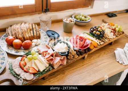 Gut angeordnete Wurstplatte auf einem Holztisch mit verschiedenen Käsesorten, Wurstwaren, Früchten, Nüssen und Brot, perfekt für gesellschaftliche Zusammenkünfte. Stockfoto