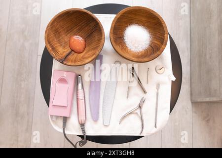 Eine geordnete Anordnung von Pedikürenwerkzeugen auf einem Tisch, einschließlich Schüsseln mit Salz und Stein, umgeben von verschiedenen Nagelpflegeinstrumenten Stockfoto
