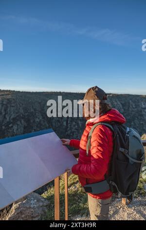 Seitenansicht einer nicht erkennbaren Vogelbeobachtung weiblicher Wanderer an einem Aussichtspunkt in Salamanca, Spanien. Sie untersucht eine Karte, während sie Outdoor-Ausrüstung trägt. Stockfoto