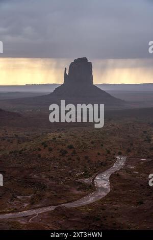 Ein stimmungsvoller Blick auf das Monument Valley, während ein Sturm Regen bringt und dramatisches Licht über die hoch aufragenden Steilwände und die Straßen darunter wirft Stockfoto