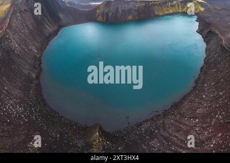 Atemberaubendes Bild mit Drohnen, das die atemberaubende Schönheit eines ruhigen vulkanischen Kratersees zeigt, eingebettet in die zerklüftete Landschaft des Islandgebirges Stockfoto