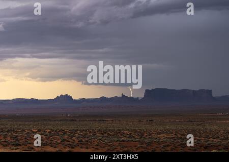 Eine dramatische Szene fängt einen Blitz in der Nähe der berühmten Buttons des Monument Valley ein, inmitten eines dunklen, stürmischen Himmels Stockfoto