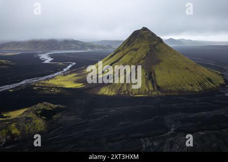 Ein atemberaubender Blick aus der Vogelperspektive auf den Vulkan Maelifell, der sich durch seine einzigartige konische Form und das lebhafte grüne Moos im Kontrast zum dunklen Vol auszeichnet Stockfoto