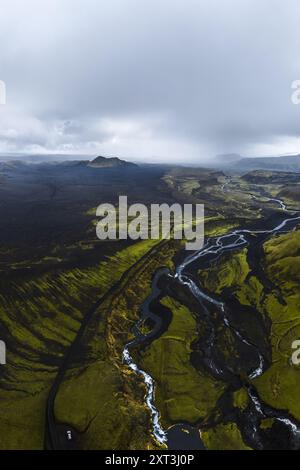 Luftaufnahme, die die starken Kontraste und die lebendigen Grüns der isländischen Highlands mit verwinkelten Flüssen, die sich durch dunkle Vulkanlandschaften ziehen, und einfangen Stockfoto