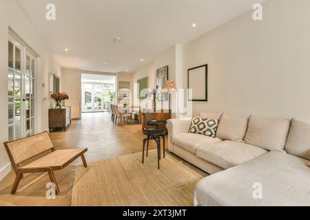 Elegantes und modernes Wohnzimmer mit gemütlichem Ecksofa, schickem Dekor, Holzmöbeln und viel Tageslicht. Stockfoto