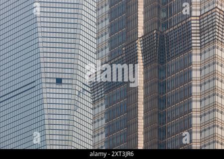 Detaillierte Ansicht des zeitgenössischen architektonischen Designs, die die Gegenüberstellung und Textur von Glasfassaden auf Hochhäusern in Shanghais geschäftigem Treiben zeigt Stockfoto