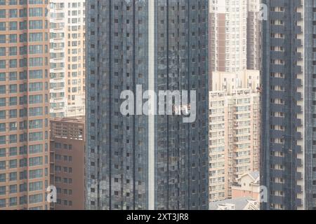 Diese Luftaufnahme erfasst eine Instandhaltungsplattform, die zwischen dicht gepackten Hochhäusern in Shanghai aufgehängt ist und die städtische Dichte repräsentiert Stockfoto