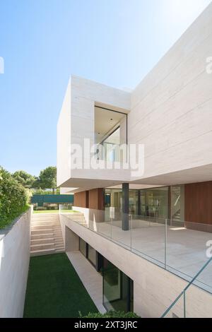 Dieses Bild zeigt ein luxuriöses, modernes Haus mit schlichter minimalistischer Architektur mit großen Glasfenstern, raffinierten Steinwänden und Holzakzenten Stockfoto