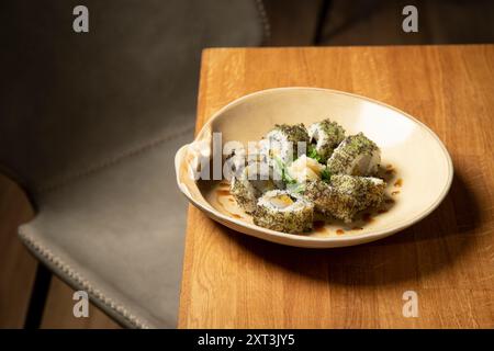 Ein elegant präsentierter Teller mit Sushi-Brötchen in einer einzigartigen Garnitur, serviert auf einer stilvollen Keramikschale auf einem Holztisch Stockfoto